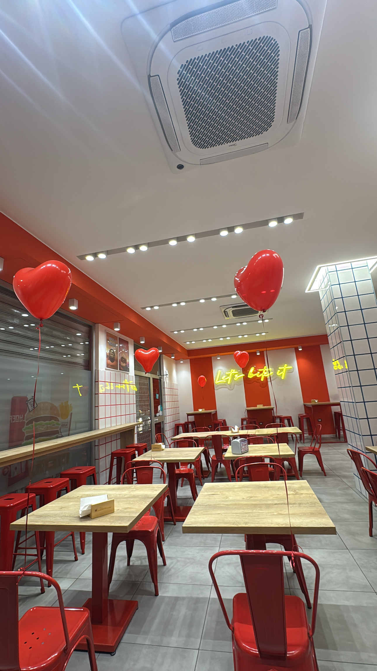 Interno del locale Slyder Burger a Santa Maria Capua Vetere, con insegna al neon "Let's bite it"